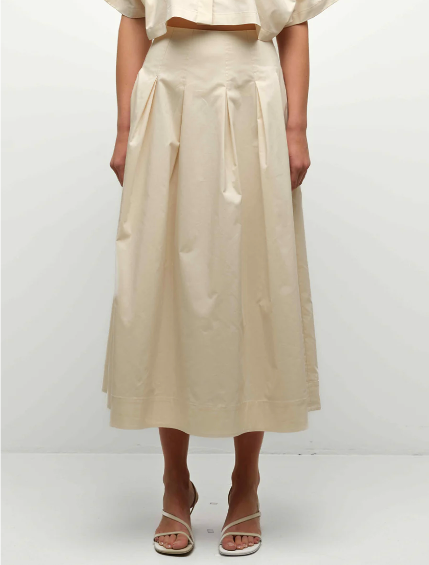 Person wearing a beige skirt and top on a white background