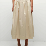 Person wearing a beige skirt and top on a white background