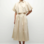Woman wearing a beige outfit with a white background
