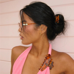 Woman wearing a pink top with decorative hair clip against a light background