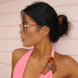 Woman wearing a pink top with decorative hair clip against a light background