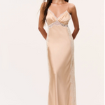 Woman in pale gold silky maxi dress with spaghetti straps on a plain background