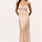 Woman in pale gold silky maxi dress with spaghetti straps on a plain background