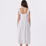 A woman viewed from the back wearing a white lace midi dress with ruffled cap sleeves and a square open back, paired with red high heels, against a plain white studio background.