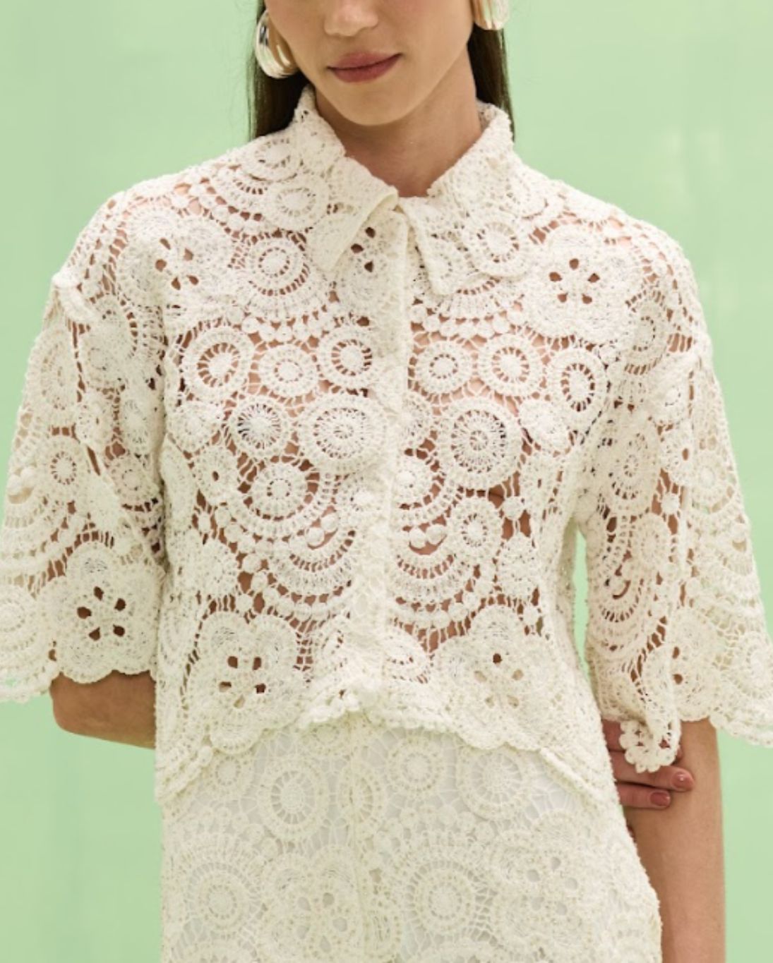 Woman wearing a white lace blouse against a light green background