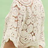 Close-up of a person wearing a white lace top against a light green background