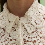 Close-up of a person wearing a white lace garment.