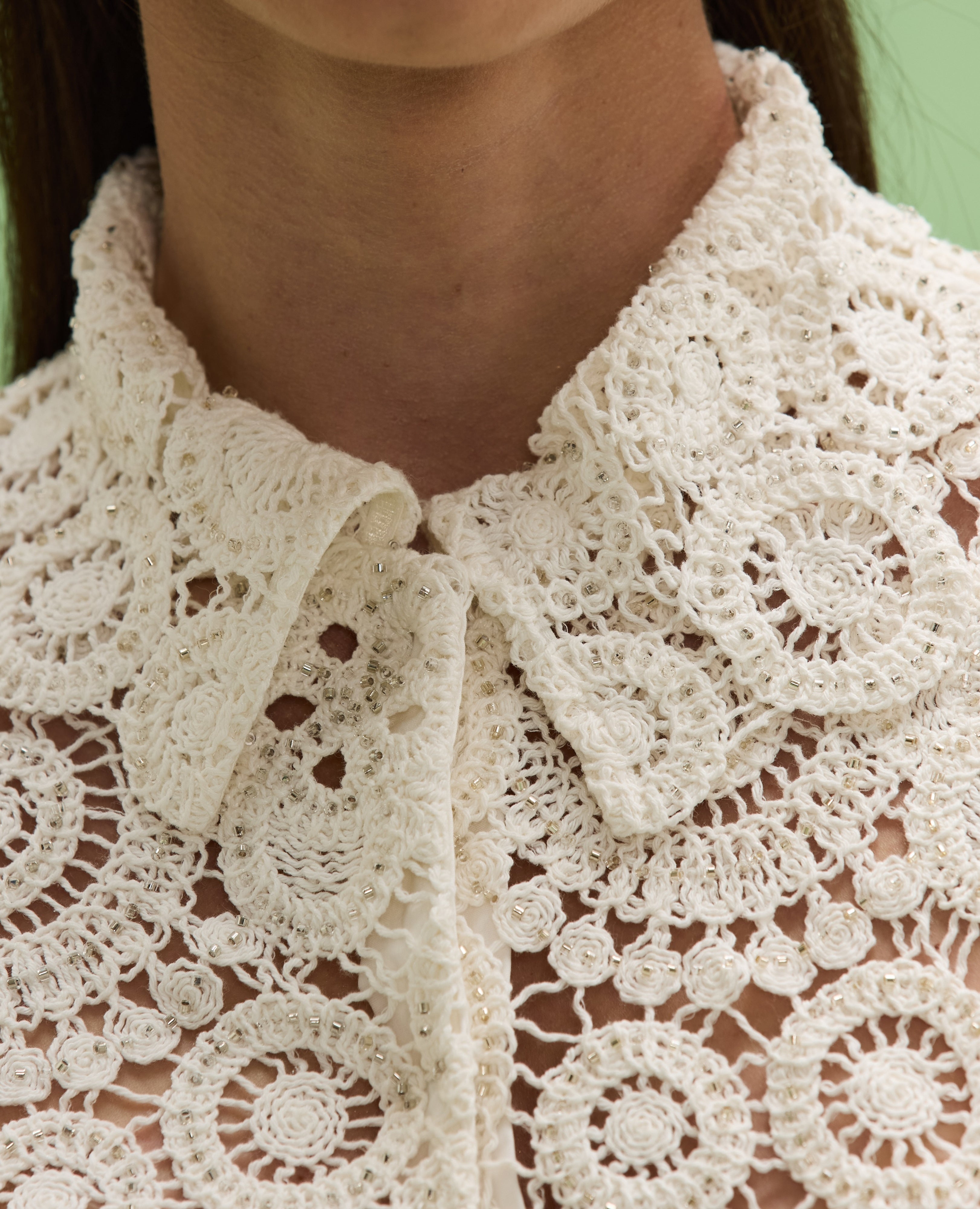 Close-up of a person wearing a white lace garment.