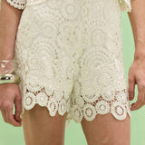 White lace shorts on a person against a light green background
