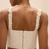 Beige lace top with pearl straps worn by a person on a beige background