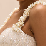 Close-up of a person wearing a pearl and sequin dress with a neutral background