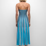 Woman wearing a strapless blue and white striped dress on a plain background