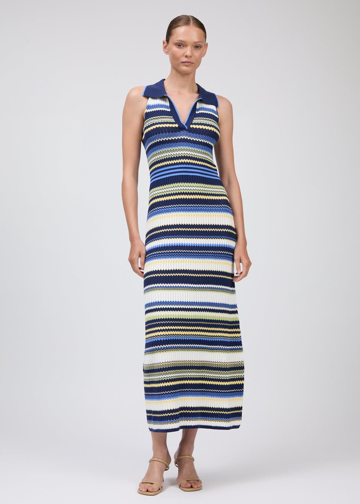 Woman wearing a long, multicolored striped dress on a white background