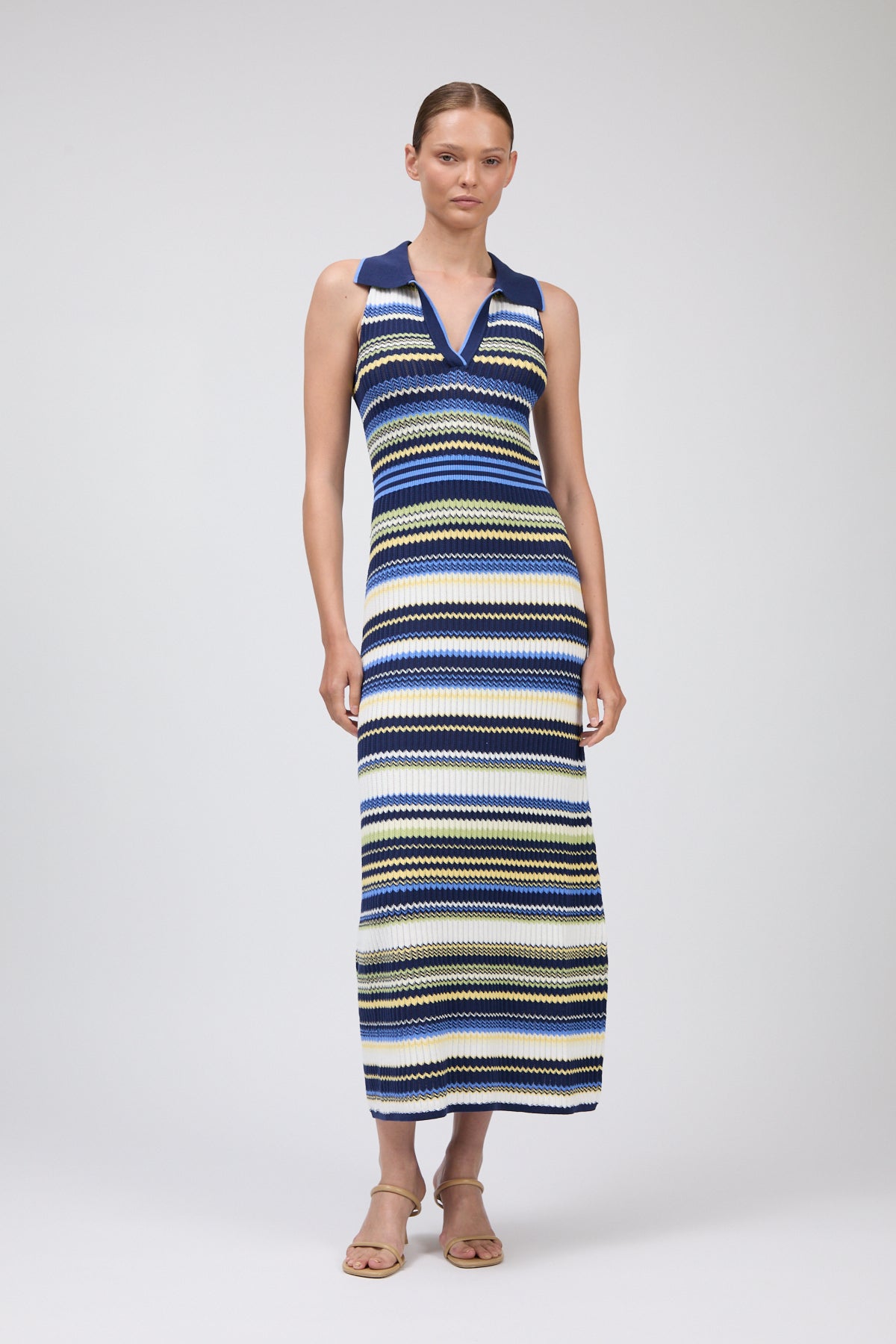 Woman wearing a long, multicolored striped dress on a white background