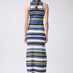 Woman wearing a long, sleeveless dress with blue and yellow stripes on a white background