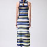 Woman wearing a long, sleeveless dress with blue and yellow stripes on a white background