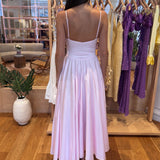 Woman wearing a light pink dress in a clothing store.