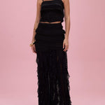 Woman wearing a black lace two-piece outfit on a pink background