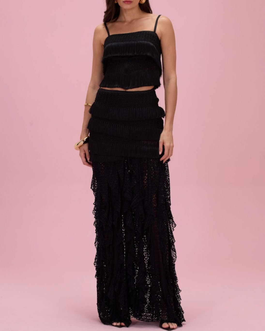 Woman wearing a black lace two-piece outfit on a pink background