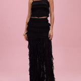 Woman wearing a black lace two-piece outfit on a pink background