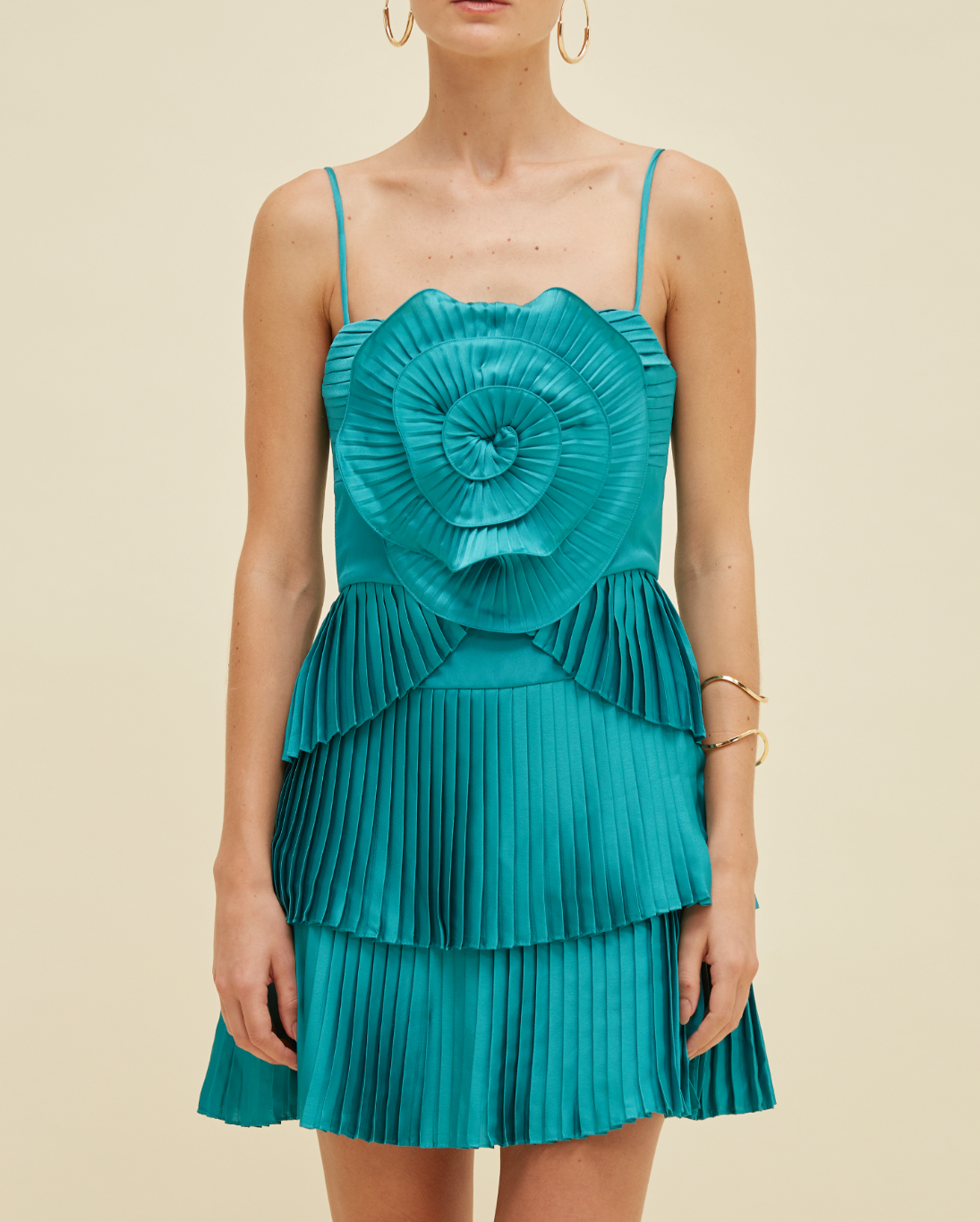 Teal dress with a large floral top and pleated skirt on a beige background