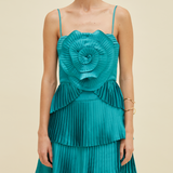 Teal dress with a large floral top and pleated skirt on a beige background