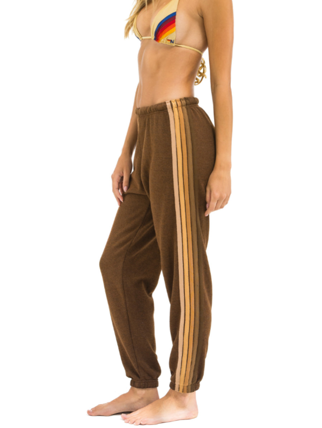 Brown sweatpants with shade of brown stripes worn by a person on a white background