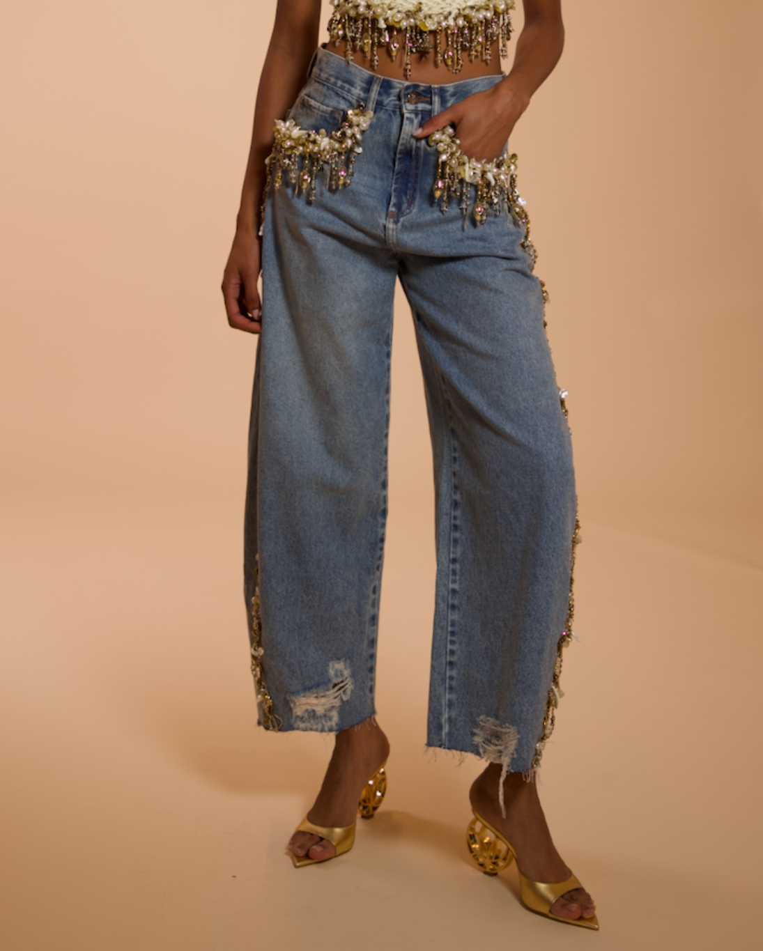Denim pants with embellishments on a beige background