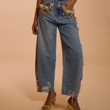Denim pants with embellishments on a beige background